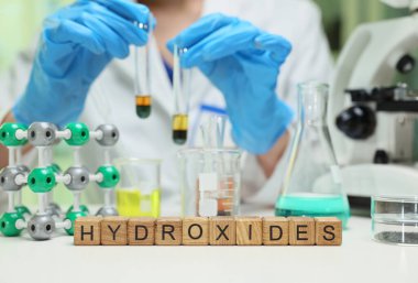 Bir laboratuvar teknisyeni hidroksitleri test tüpleri ve çeşitli moleküler modeller kullanarak detaylı bir çalışma yürütür.