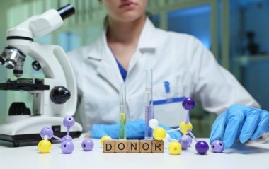 Bir bilim adamı moleküler modeller üzerinde çalışıyor ve bir laboratuvarda gelişmiş bir mikroskop kullanarak donör araştırmalarına odaklanıyor.