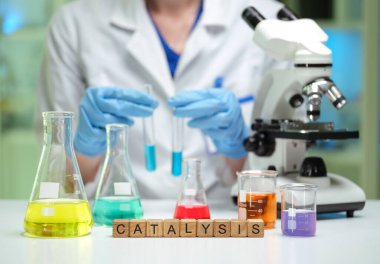 Bir bilim adamı, çeşitli renkli sıvılar ve mikroskop kullanarak detaylı bir kimyasal analiz yapıyor.