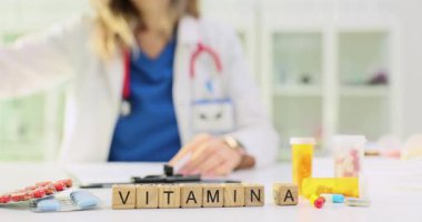 A vitamini haplar ve şişelerle çevrili tahta küplere yazılmış. Parlak elementler beslenme odağı ve destek konseptini temsil eder