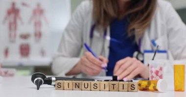 Sinüzit kelimesi ahşap bloklardan yapılmış, ENT aletleri ve ilaç bardağının yanına konmuş. Tıbbi nesneler sinüsle ilgili tanı ve hasta tedavisini vurguluyor