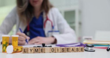 Tahta küpler, ilaç şişeleri ve steteskopun yanında Lyme hastalığı oluşturur. Yeşil kapsüller ve araçlar bakteriyel enfeksiyon ve uzun süreli tedaviye işaret ediyor