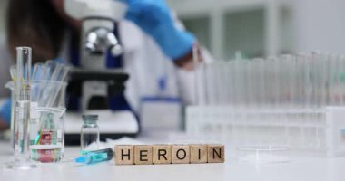 Tıp laboratuarındaki doktora karşı şırıngalı ve kimyasallı eroin. Kadın bilim adamı mikroskopta laboratuarda ilaçları analiz ediyor.