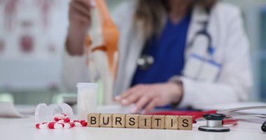Bloklarda Bursitis ve kadın doktor diz ekleminin anatomik modelini sunuyor. Kadın doktor, tıp bürosunda öğrenciler için kemik hastalıklarını açıklıyor