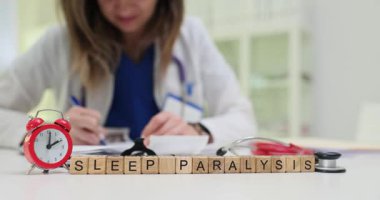 Doktor işyerindeki alarmlı tahta küplerin yazılı olduğu uyku felci. Kadın hekim, klinikteki hastaya yardım etmek için reçete yazar