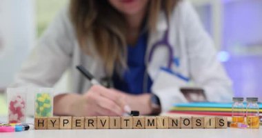 Tahta bloklar, doktor masasında renkli besinlerin yanında hipervitaminli kelime oluşturur. Doktorlar aşırı doz vitamin sonuçlarını kontrol eden bir plan yazdılar.