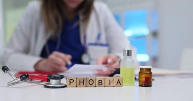 Tahta bloklar, küçük şişe ve steteskopun yanında duran fobiyi haber yapar. Psikolog, masadaki hastanın endişe tedavisini inceleyen notlar yazıyor.