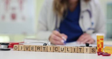 Tahta küpler turuncu hap şişesi ve panonun yanına yerleştirilmiş Divertikülit kelimesini heceliyorlar. Kapsüller sindirim iltihabı teşhisi koyuyor.