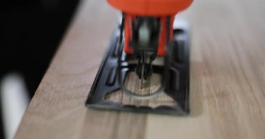 Modern güçlü elektrikli yapboz, ahşap tahtada, tezgahın üzerine kesin bir kesik atar. Manüel kesici marangozluk atölyesinde kereste kalkanı kesiyor. Yapı çalışması