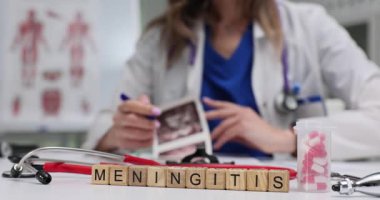 Laboratuvar önlüklü kadın masasında menenjit olan tahta blokların yakınındaki ultrason taramalarıyla çalışıyor. İltihaplı hastalığın teşhisi ve tedavisine odaklanın