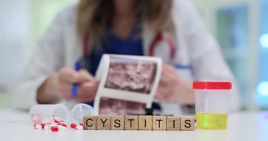 Masada parlayan ışık, tahta bloklardan yapılan sistit kelimesine odaklanıyor. Kadın tıp çalışanı ultrason görüntüsü tutuyor. Mesane sorununu araştırıyor.