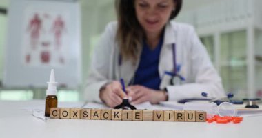 Tahta küplere göre Coxsackie virüsü enfeksiyon temasını tıbbi objelerle sunuyor. Doktor, hastalıklar etrafında profesyonel atmosfer yaratan notlar yazıyor.