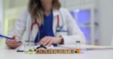 Tahta küpler panzehir fikrine masadaki şişelerle bağlanıyor. Kadın tıp uzmanı tedavi için umut ortamı yarattığını belirtiyor.