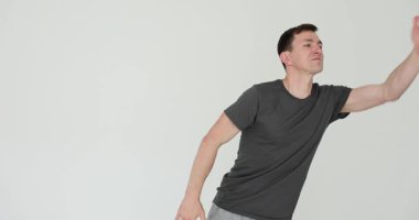 Siyah tişörtlü mutlu adam beyaz duvardan atlayan ellerle öpücük yolluyor. İletken sevgi dolu selamlama ve şakacı etkileşim yavaş çekim