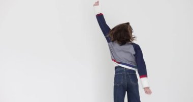 Kazaklı ve kot pantolonlu genç kız zıplıyor ve dans ediyor. Photoshoot yavaş çekim sırasında gençlik enerjisi, neşe ve dinamik ifade duygusu