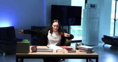 Kadın çalışan spor ceket giyer ve ofis malzemeleriyle ahşap masada kağıtlarla çalışmaya başlar. Odaklanmış üretkenlik ve organizasyonun özü