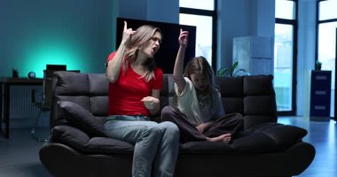 Mutlu anne koltukta dans ederek neşeli bir ruh hali yaratıyor. Kız gülümseyerek ritmi takip eder ve ağır çekimde neşeli ve oturarak kalır.