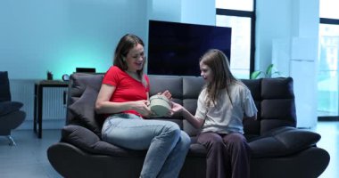 Genç kız kalp şeklindeki kutuyu dokunaklı bir sürpriz yaratacak bir kadına uzattı. Annem elinde ağır çekimde sembolik bir hediye tutarken gülümserken çok şaşırmış görünüyor.