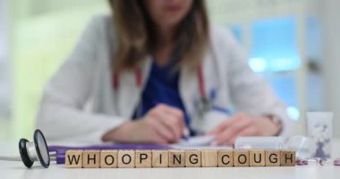 Tahta küplere göre boğmaca, hastalık bilinci arttırıyor doktor raporu yazarken. İlaçlar ve steteskop tıbbi tedaviyi gösteriyor.