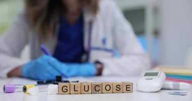 Tahta küplerdeki glikoz kelimesi şeker seviyesinin izlenmesini vurguluyor. Kan sayacı ve test tüpleri doktor teşhisi ile tıbbi temayı güçlendiriyor