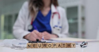 Kadın tıp uzmanı, masadaki tahta bloklar üzerinde nöropati yakınında notlar alıyor. Klinikte nöropatinin nöroloji araştırması ve tedavisi