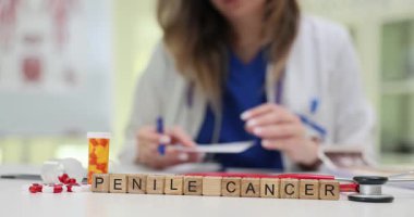 Palto giyen tıp uzmanı, Penis Kanseri yakınında bloklara reçete yazıyor ve masasında haplar var. Erkek sağlığı ve onkoloji teşhisi ve tedavisi