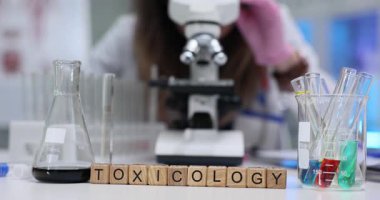 Pembe eldivenli bilimadamı, mikroskopla, küp ve cam üzerinde toksikoloji bölümüne bakıyor. Laboratuvarda toksikoloji bilimine odaklan.