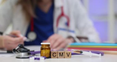 Kadın doktor, CMV yakınlarındaki belgeleri ahşap bloklarda ve masadaki hapları inceliyor. Sitomegalovirüsle ilgili virüs teşhisi ve tedavisi