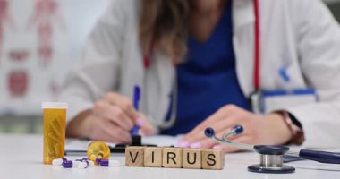 Kadın doktor Virüs 'ün yanında tahta bloklara reçete yazıyor ve masadaki haplara. Tıbbi ortamdaki viral enfeksiyonların teşhisi ve tedavisi