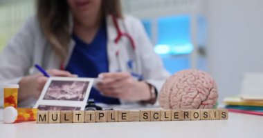 Kadın doktor bloklardaki çoklu skleroz yakınlarındaki ultrason taramalarını ve masadaki beyin modelini inceliyor. Teşhis ve araştırma nörolojik sağlığa odaklanıyor