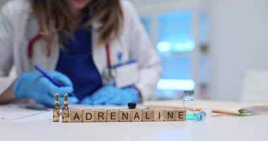 Küpler, doktorun yakınında tıbbi ampullerle çevrili Adrenalin sözcüğü gösteriyor. Söylentilere göre acil vücut tepkisi laboratuvar ortamında ve hassas araçlarda yansıtılıyor.