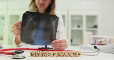 Tahta bloklardaki Mycoplasma X-ray görüntüsünü tutan kadın bir profesyonelin elinde. Tıbbi bağlamda, akciğerleri etkileyen micoplazma enfeksiyonlarının teşhisi üzerinde duruldu.