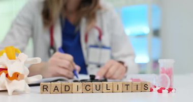Laboratuvar önlüklü kadın Radiculitis yakınlarındaki dokümanlara masa üstündeki tahta küplere yazı yazıyor. Omurga modeli omurilik sinir kökü iltihabı teşhisi koyuyor.