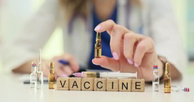 Bayan doktor ampulü ahşap bloklarla, aşıyla ve şırıngayla birlikte masasında tutuyor. Modern klinikte aşılama ve halk sağlığı teması