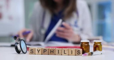 Tahta küplerde frengi kahverengi cam şişeler ve steteskopun yanında duruyor. Kadın doktor klinikteki enfeksiyon sorununu araştıran notlar yazıyor.