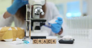 Tahta küplere göre çatlak mikroskop yakınında temiz bir laboratuvar masasında yatıyor. Bilim adamı kimyasal sorunu araştıran tehlikeli narkotik örnekleri inceliyor.