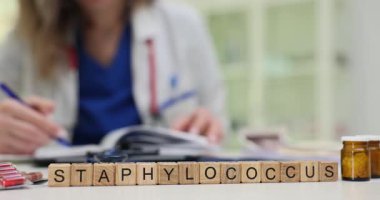 Tahta küplere göre Staphylococcus tıbbi malzeme ve dosya tarafından yerleştirilmiş. Ceketli kadın bakteriyel sorun araştırmasını kontrol eden belgeleri inceliyor