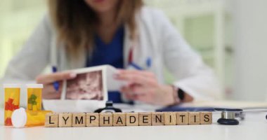 Tahta küpler ultrason görüntüsüyle hastane masasında lenf iltihabı oluşturur. Kadın sıhhiye klinikteki şişmiş lenf düğümünü araştıran taramaları kontrol ediyor.