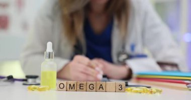 Omega-3 kelimesi, sarı yağ şişesi ve kapsüllerle ahşap küplere yerleştirilmiş. Kadın uzmanlar, hastalar için sağlık rehberi hazırlayan takviyeler düzenlerler.