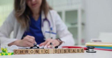 Küplere yazılan kronik hastalık ifadesi hapların ve steteskopun yanına konur. Söz, devam eden bakım ve izleme gerektiren uzun vadeli koşullarla ilgilidir