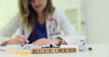 Tahta küplere yerleştirilmiş baş döndürücü sözcük ilaç organizatörü ve plastik tüplerin yanına konur. Sahne istikrarsızlığa ve nörolojik kontrol ihtiyacına işaret ediyor