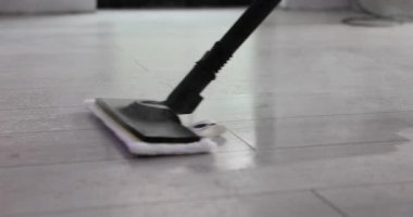 Ev hanımı buharlı paspası yavaşça fayanslı zeminde gezdirip görünür kirleri dikkatlice temizliyor. Güçlü buhar jeti zemindeki yapışkan toprağı temizler.