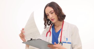 Doktor beyaz arka plandaki hastanın test sonuçlarını inceliyor. Kadın, hastanın sağlık durumunu anlamak için kan testinin sonuçlarını iyice okur.