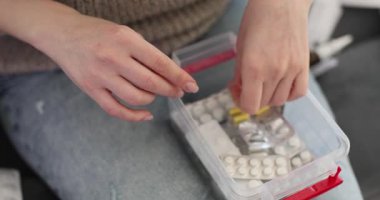 Eller, ilaç kutusundaki yataktaki tabletlere bakar. Kadın kabarcıkları kenara çeker ve yavaş çekim yapmadan önce gerekli dozajı hazırlayan haplar bulur.