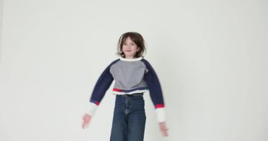 Genç kız büyük bir enerjiyle zıplar ellerini havaya kaldırır ve neşeyle alkışlar. Neşeli çocuk heyecandan zıplıyor. Yavaş çekim