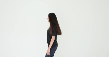 Uzun siyah saçlı, günlük kıyafetleri olan bir kadın beyaz arka planda dönüp duruyor. Dişi aynı noktada şakacı bir şekilde dönüyor. Yavaş çekim