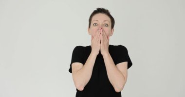 Korkmuş kadın elleri ve soluğu beyaz arka planda olan ağzı saklıyor. Dişi, beklenmedik bir sesten ürkmüş dudakların üzerinde sıkıca el ele tutuşur.