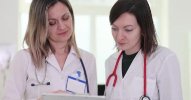 Kadın doktorlar panodaki hastanın test sonuçlarını dikkatle incelerler. Konsantre doktorlar tedavinin devamı hakkında tartışmaya başlarlar. Yavaş çekim