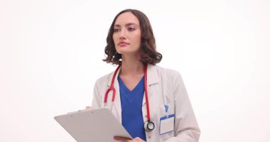 Kadın doktor hastayı dinler ve beyaz arka planla ilgili detaylı notlar alır. Kadın bilgileri notlara kaydediyor. Yavaş çekim