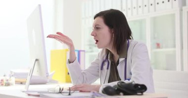 Kadın doktor bilgisayar ekranına bakıyor ve hayal kırıklığı içinde başını tutuyor. Doktorlar ellerini kafalarına koyuyorlar ve tıbbi kayıtları monitörde okuyorlar.